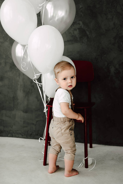 Портрет прекрасного маленького хлопчика щасливий усміхнений, що святкує 1 рік народження. Однорічний європейський маленький джентльмен грає з повітряними кульками
 - Фото, зображення