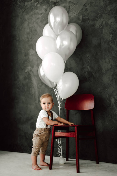 Muotokuva ihana pieni poika onnellinen hymyillen juhlii 1 vuosi syntymäpäivä. Vuoden vanha eurooppalainen pikku herrasmies leikkii balooneilla
 - Valokuva, kuva
