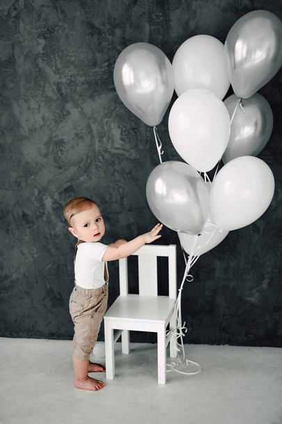 Портрет прекрасного маленького хлопчика щасливий усміхнений, що святкує 1 рік народження. Однорічний європейський маленький джентльмен грає з повітряними кульками
 - Фото, зображення