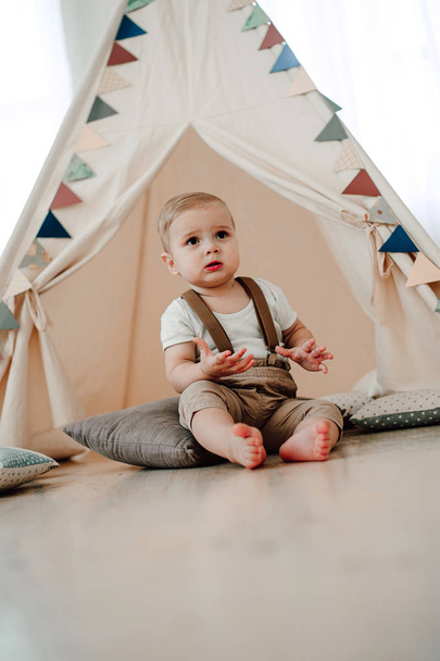 素敵な小さな少年笑顔祝う 1 年誕生日の肖像画。赤ちゃんテント ウィグワムで座っている 1 歳のヨーロッパほとんどの紳士 - 写真・画像