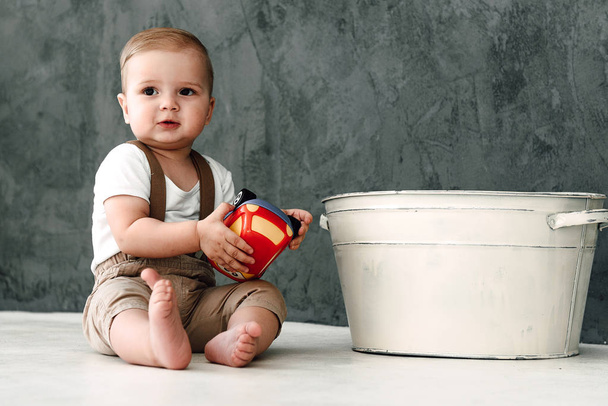 Портрет прекрасний маленький хлопчик з усміхнений святкування 1 рік днем народження. Один-річного європейської хлопчика сидячи на підлозі в студії - Фото, зображення