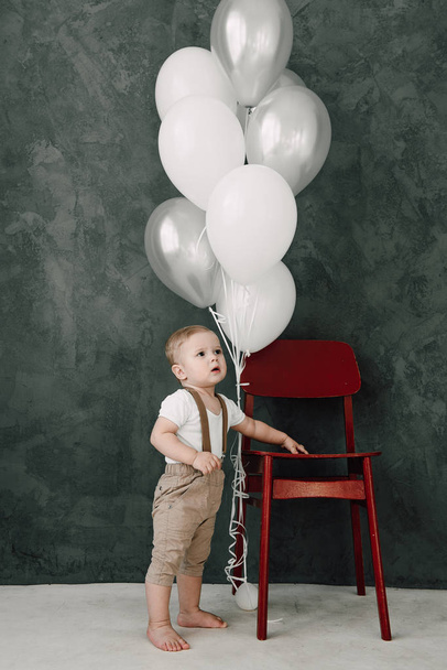 Retrato del adorable niño feliz sonriendo celebrando 1 año de cumpleaños. Un pequeño caballero europeo de un año jugando con globos
 - Foto, Imagen