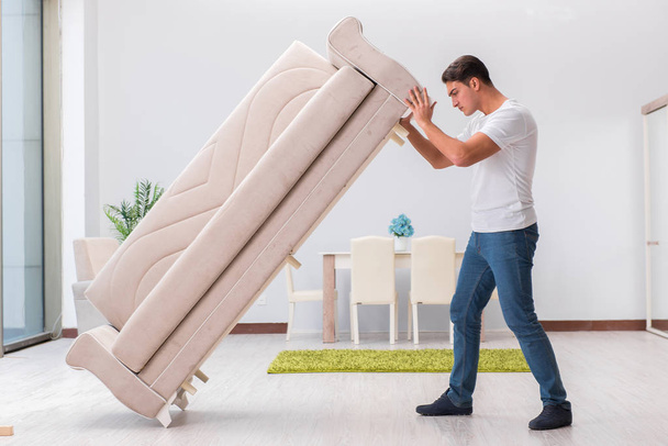 Чоловік рухає меблі вдома
 - Фото, зображення