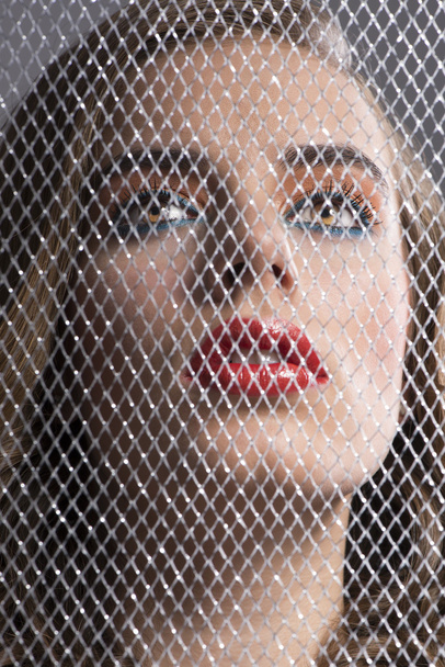 portrait of girl behind net looks up - Фото, изображение