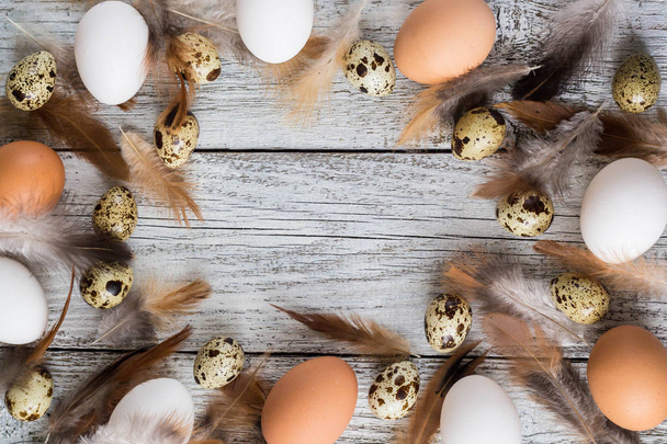 イースターの卵と鶏の羽根から作られたイースターの背景 - 写真・画像