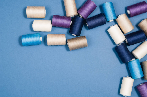 Top view of colorful thread spools over blue background - Zdjęcie, obraz