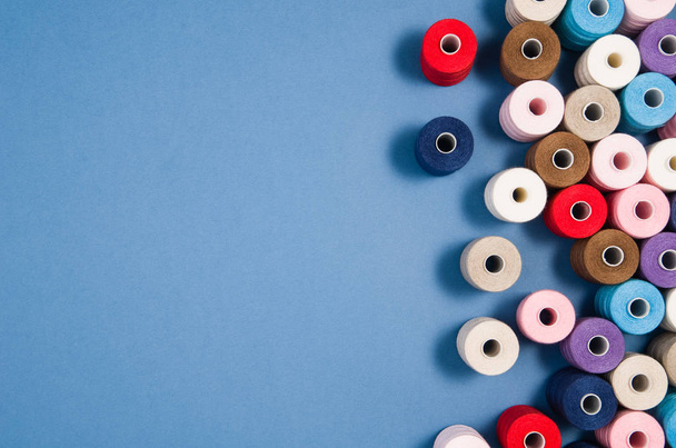 Top view of colorful thread spools over blue background - Zdjęcie, obraz