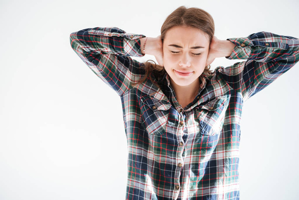 Frowning stressed woman in plaid shirt covered ears by hands - Φωτογραφία, εικόνα