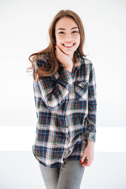 Happy charming young woman in plaid shirt standing and posing - Fotó, kép