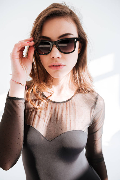 Young beautiful lady wearing sunglasses standing at studio - 写真・画像