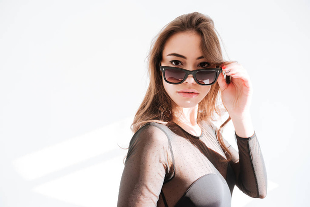 Attractive lady wearing sunglasses standing at studio - Фото, изображение