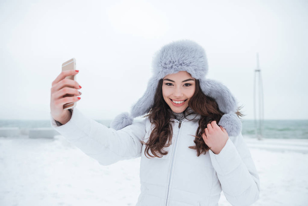 Cheerful woman wearing hat make selfie by her phone. - Foto, Imagen