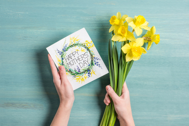 Card and daffodils in hands - Photo, Image