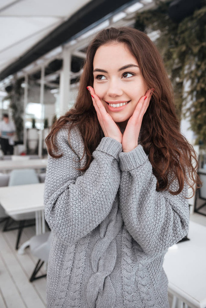 Cute young lady dressed in sweater sitting in cafe - 写真・画像
