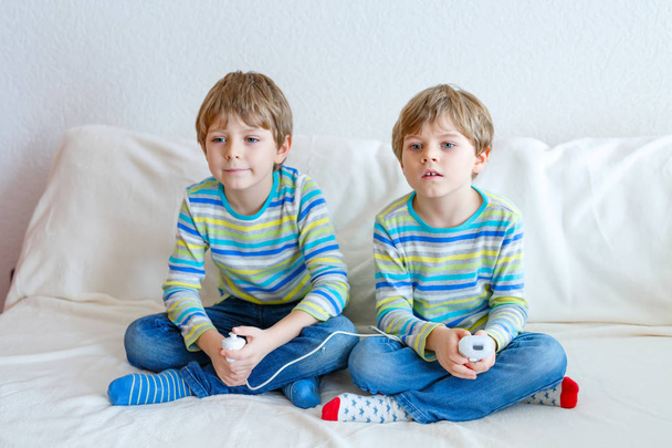 Два маленьких мальчика играют дома в видеоигры
 - Фото, изображение
