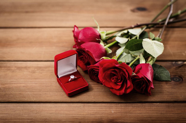 close up of diamond engagement ring and red roses - Foto, afbeelding