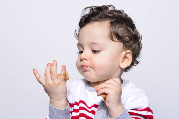 Portrait of a cute baby eating a biscuit looking at the hand. - Foto, Imagem