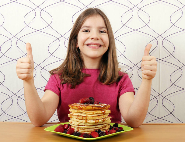 happy little girl with pancakes and thumbs up - 写真・画像