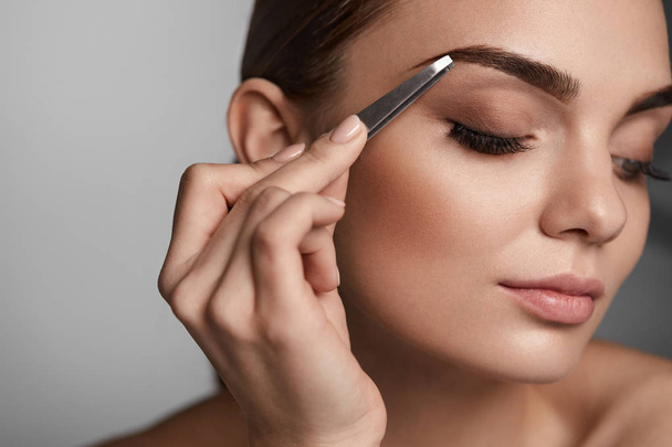 Woman With Closed Eyes And Tweezers For Eyebrows. Beauty Tools - Fotoğraf, Görsel