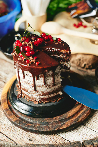 Шоколадный торт с красными ягодами смородины на старом деревянном столе
 - Фото, изображение