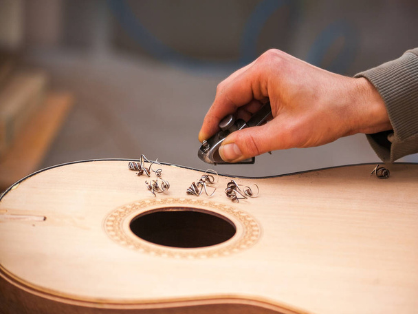 Serious professional guitar-maker working with unfinished guitar at workshop - Фото, изображение