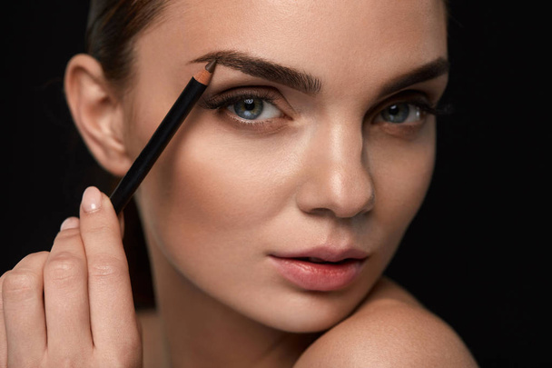 Beautiful Woman Contouring Eyebrows With Pencil. Beauty  - 写真・画像