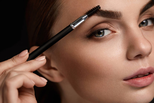 Beautiful Woman Brushing Eyebrows With Brush. Beauty  - Фото, изображение