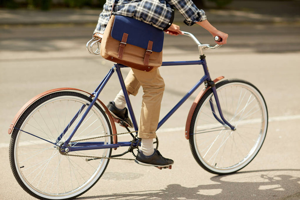 young hipster man with bag riding fixed gear bike - Fotó, kép