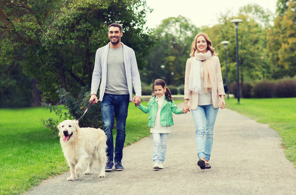 happy family with labrador retriever dog in park - Zdjęcie, obraz