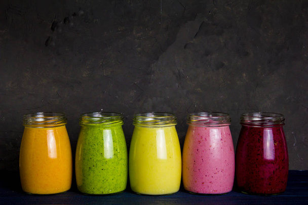 Gezond kleurrijk fruit smoothie set: smoothie met aardbeien, bramen, spinazie, banaan, wortel en ananas - Foto, afbeelding