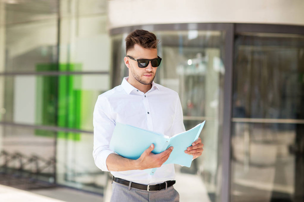 young man with business file on city street - Photo, Image