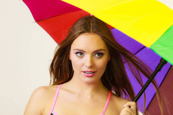 色鮮やかなレインボーの傘の下で立っている女性 - 写真・画像