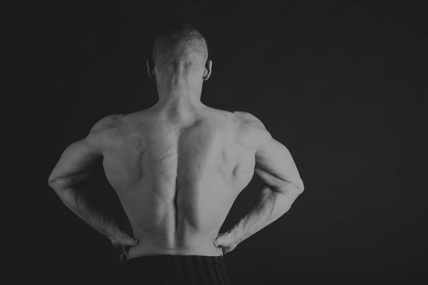 Man with dumbbells on a black and white photo. - Foto, afbeelding