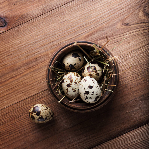 Перепелиные яйца в деревянной миске на столе
 - Фото, изображение