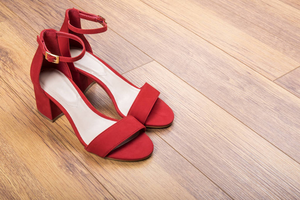 Sandalias de gamuza roja para mujer en suelo de madera
 - Foto, Imagen