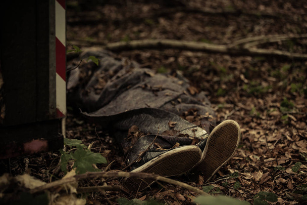 Lichaam van een dode persoon liggend in bos detritus - Foto, afbeelding