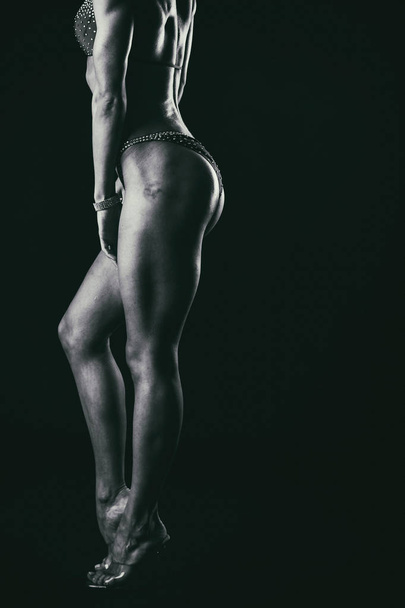 Entrenamiento elegante, mujer musculosa sobre un fondo negro
 - Foto, Imagen