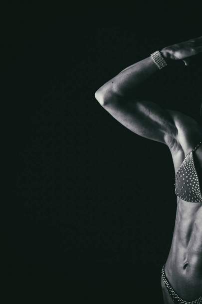 Elegant training, muscular woman on a black background - Foto, immagini