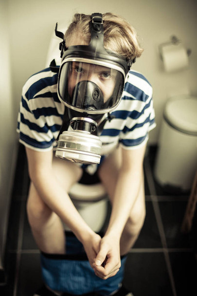 Young boy on toilet wearing gas mask - Photo, Image