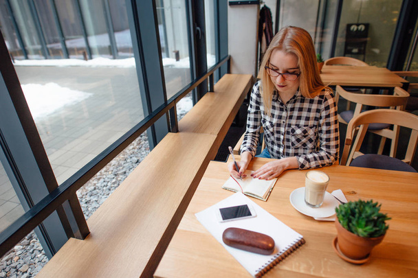 Blonde busuness vrouw zitten op de stoel in café plaats - Foto, afbeelding
