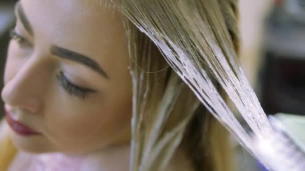 Stylist Studio beauty cause hair dye on blond strands. Closeup - Filmmaterial, Video