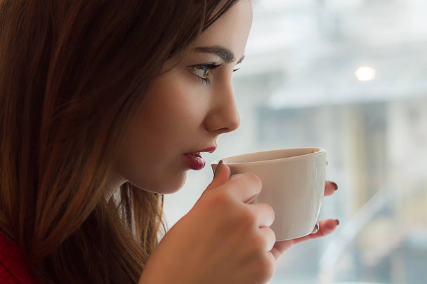  Νεαρό κορίτσι πίνει τσάι από smal κύπελλο καφέ - Φωτογραφία, εικόνα
