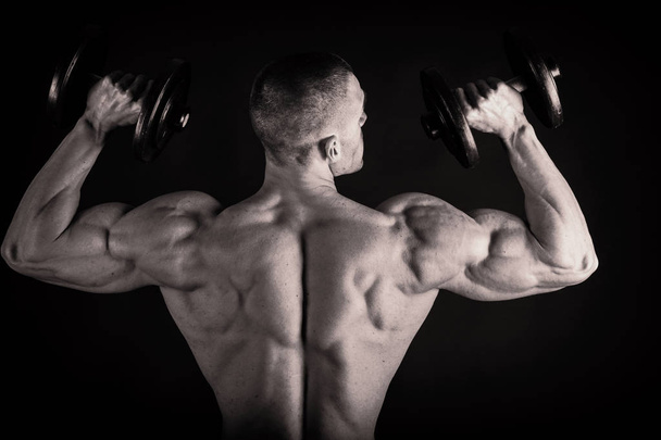 Fisiculturista mostrando suas costas e músculos bíceps, fitnes pessoais
 - Foto, Imagem