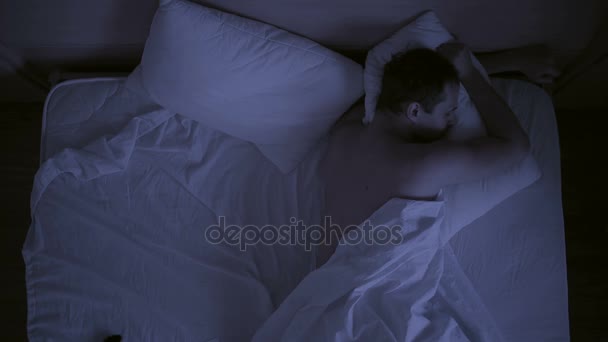Insomnia concept. man in bed at night can not sleep - Кадры, видео