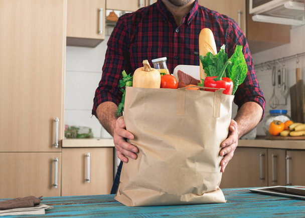Man holding full paper bag of different healthy food - Photo, image