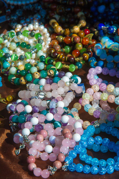 weibliche Perlen. ein kleines Stück Glas, Stein oder ähnliches Material, typischerweise gerundet und perforiert, um es mit anderen als Halskette oder Rosenkranz einzufädeln oder auf Stoff zu nähen. - Foto, Bild