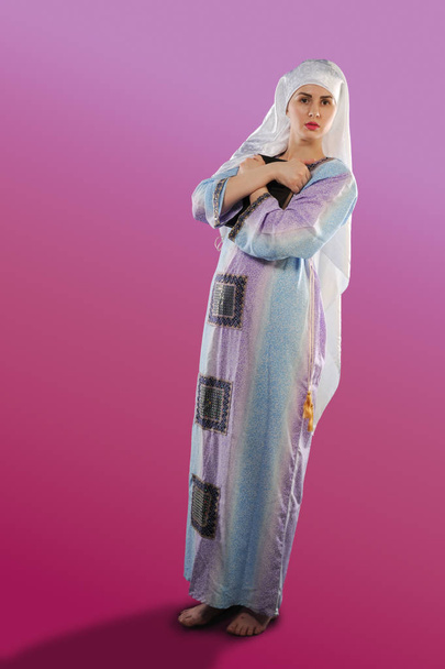 krásná dívka, Muslim. na sobě hidžáb. Obrázek muslimská dívka drží qoran. Vertikální portrét krásné muslimské dívky. V rukou dívky Korán - Fotografie, Obrázek