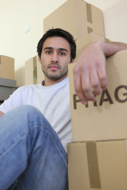 Jeune homme entouré de boîtes en carton le jour du déménagement
 - Photo, image