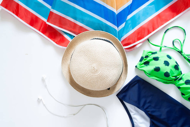 Colocación plana de artículos de verano, paraguas colorido, sombrero y traje de baño en
 - Foto, imagen
