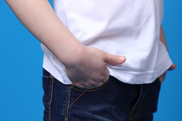 girl put her hands in the pockets of his jeans. isolated on blue background - Φωτογραφία, εικόνα